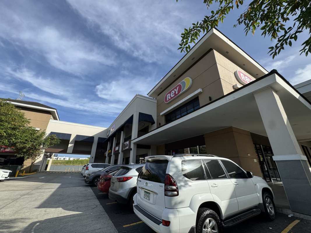Commercial plaza two-level structure with parking lot and tall signage near Rey supermarket Panama City