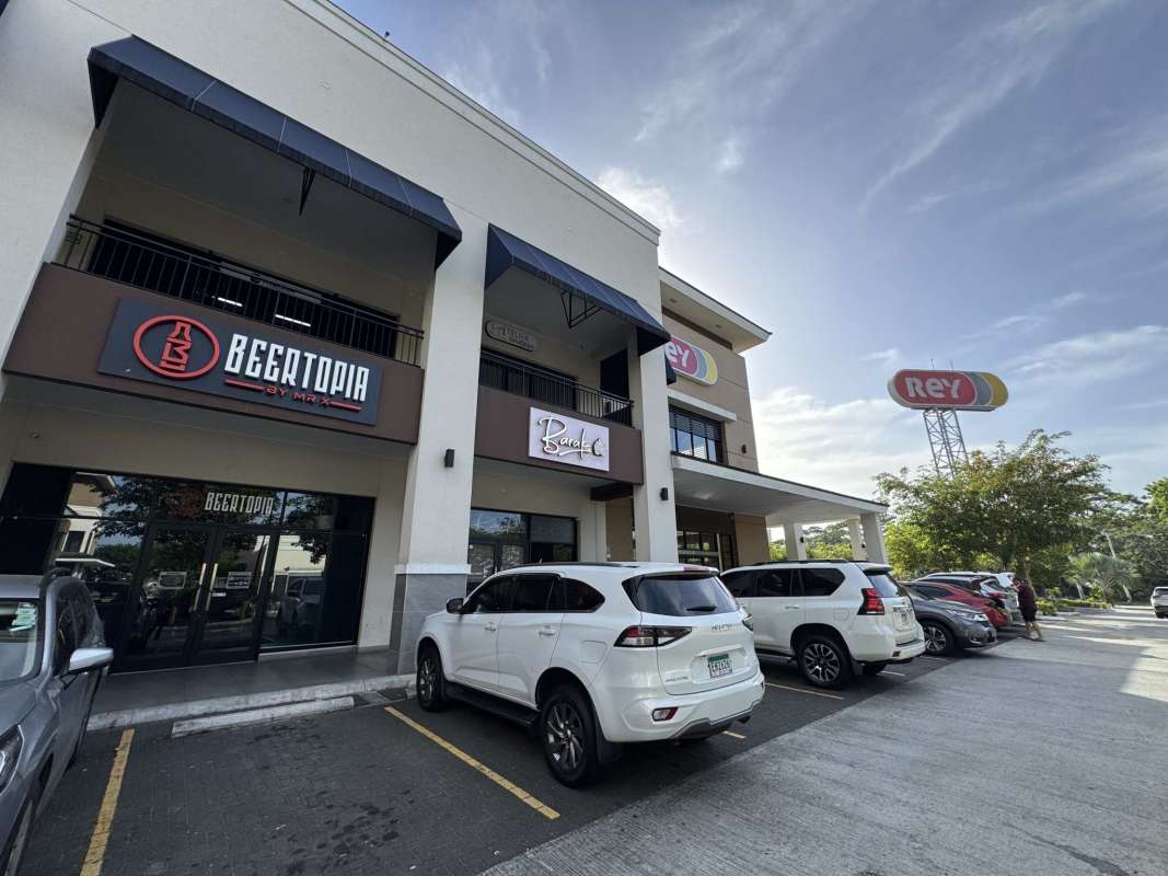 Shopping plaza exterior view with signage Rey supermarket and balcony storefronts Brisas del Golf Panama