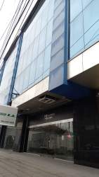 Outside view of commercial building with reflective glass facade and blue accents Zona Libre Colón Panama