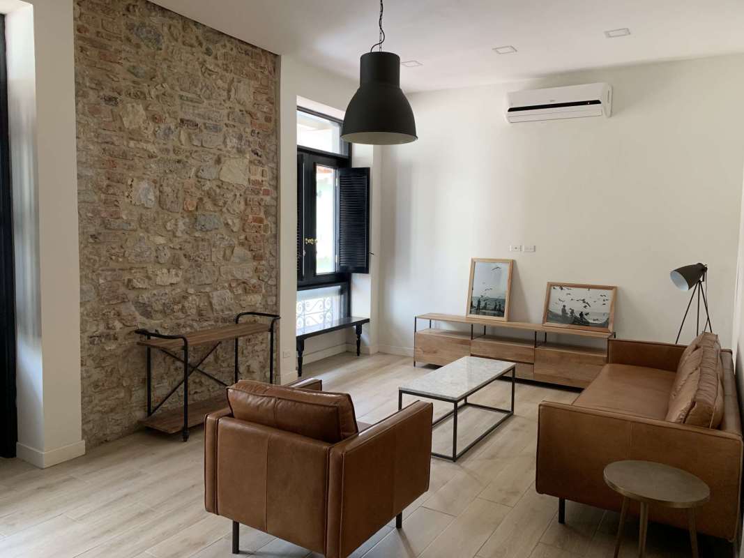 Living area with exposed brick wall, leather sofa, pendant lights in Casco Viejo St. Georges building Panama