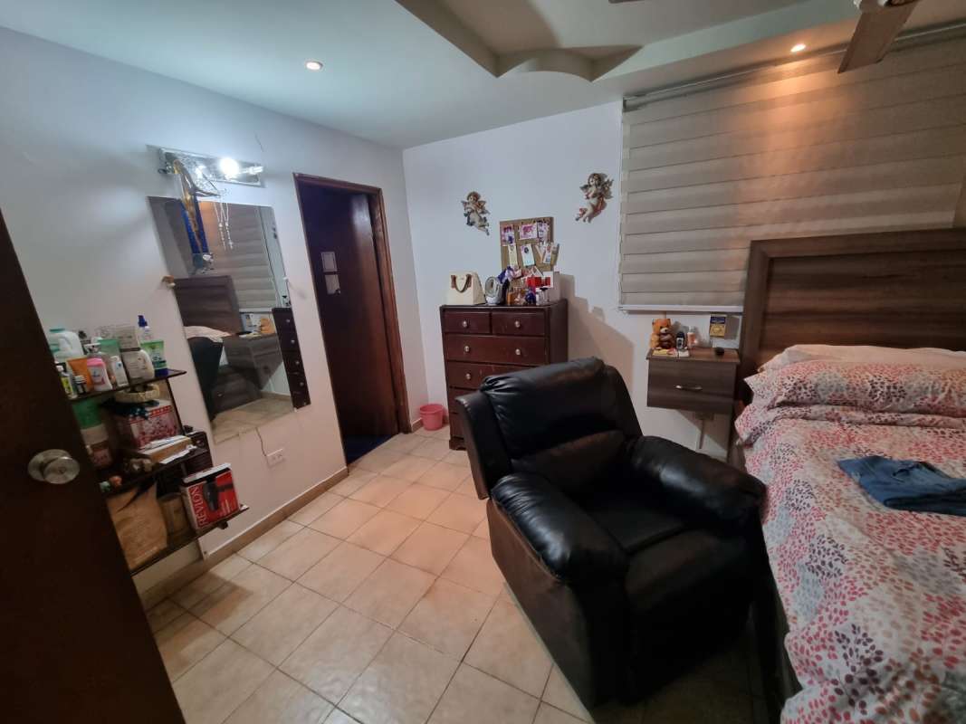 Comfortable bedroom with large window, black armchair, decorated walls at Don Bosco house San Miguelito