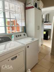 Single-story corner home with white fence, palm trees, tiled roof, driveway gate Villa María David