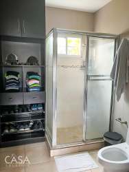 Modern bathroom with glass shower enclosure, built-in shelving, and window Villa María David Panama