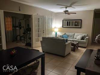 Contemporary living room with glass French doors, ceiling fan, sofa, and bright decor in Villa María David Panama