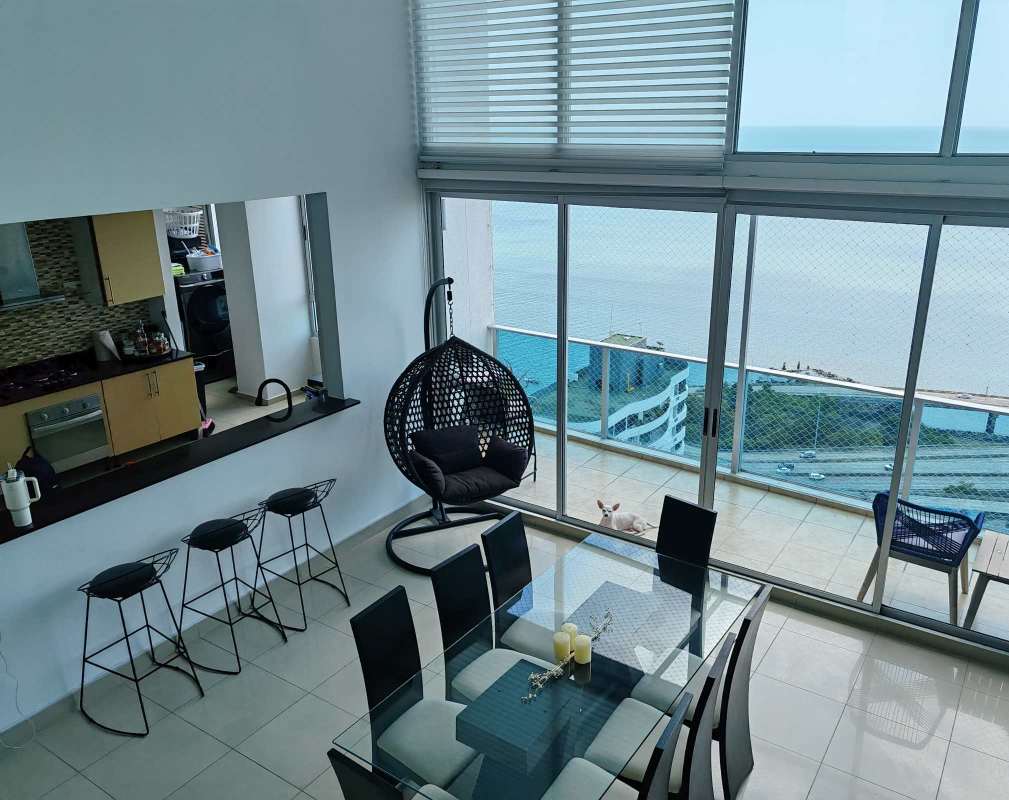 Open living dining with floor to ceiling windows, staircase and panoramic ocean views at Coco del Mar Panama