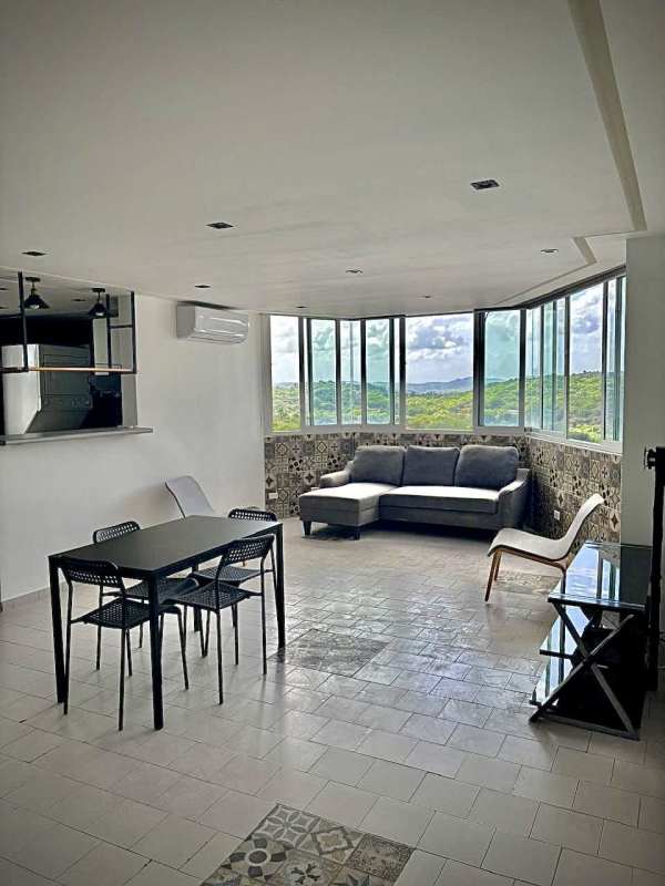 Dining room with gray sectional sofa and glass coffee table in apartment Villa de las Fuentes Panama City