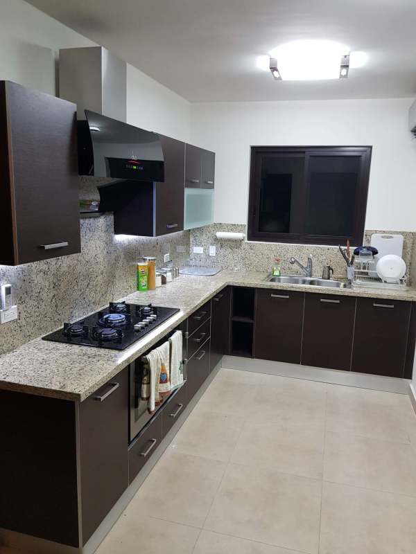 Granite countertop kitchen with gas stove, hood, cabinets and window Embassy Village Panama