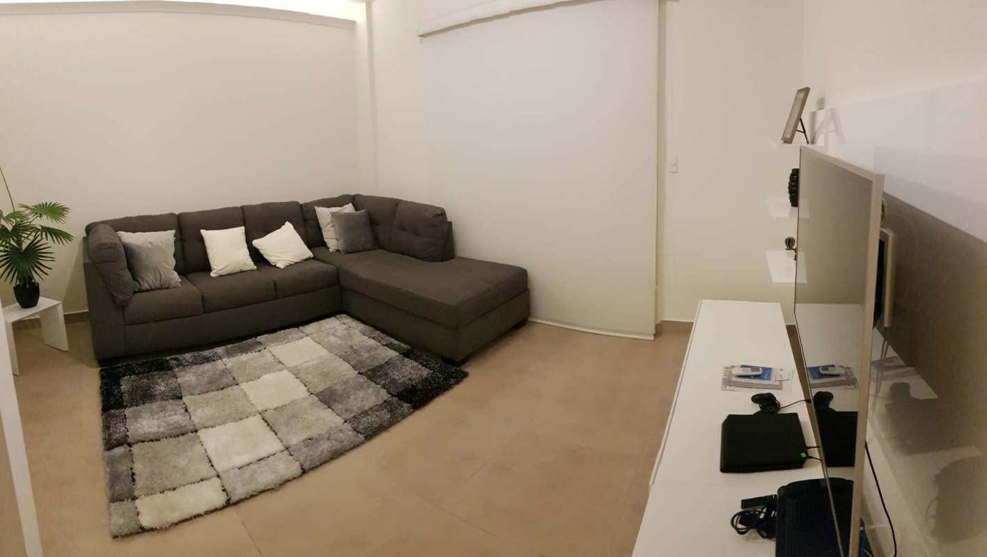 Modern living room with sectional sofa, TV unit, wall shelves and large window Clayton Panama