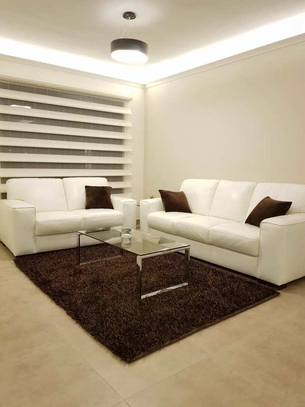 Bright living room with blinds, white sofas, brown decor, and ceiling lighting at Embassy Village Clayton