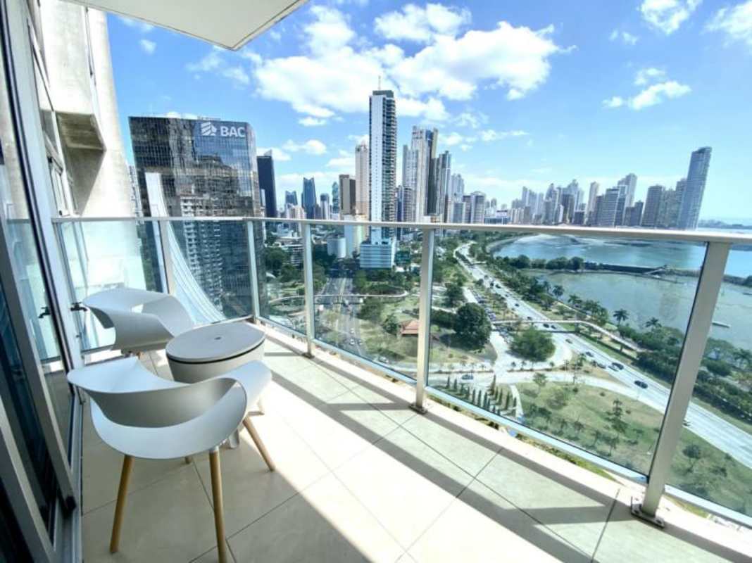 Private balcony with white chairs and table overlooking Panama’s skyline and waterfront at PH White