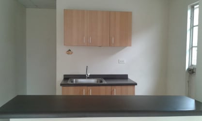 Modern compact kitchen with wood cabinetry and black countertop in house for rent Costa Verde Panama