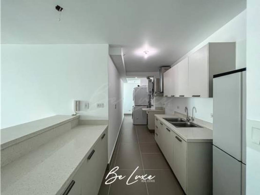 Modern minimalist kitchen with ample cabinetry and integrated laundry area at Altamira Residences in Bella Vista