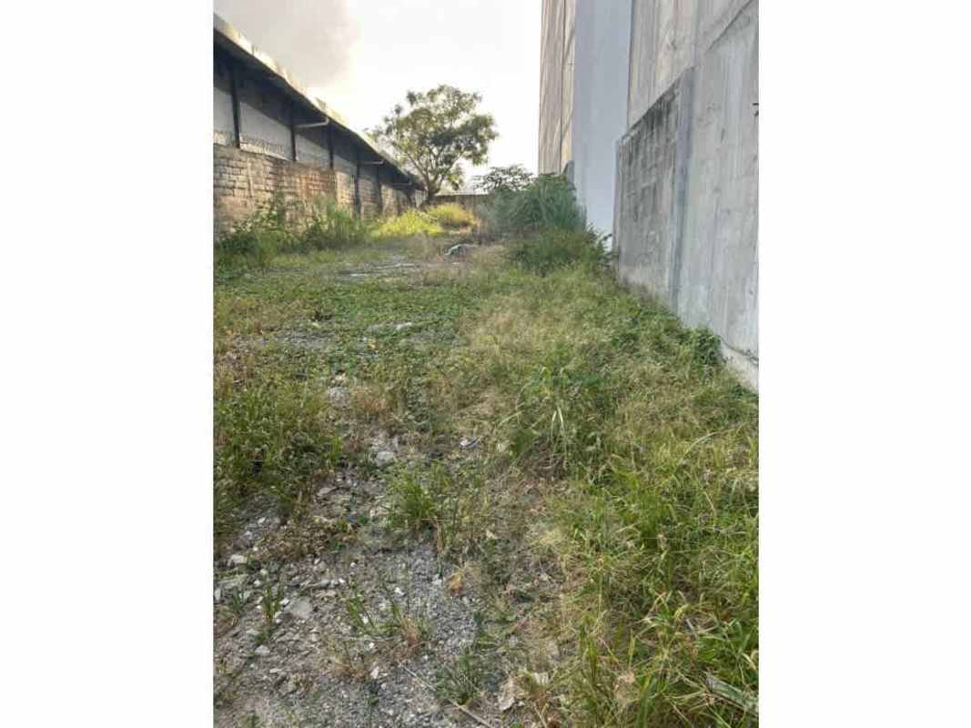 View of buildable fenced land with perimeter concrete wall and open gate in Río Abajo Panama City
