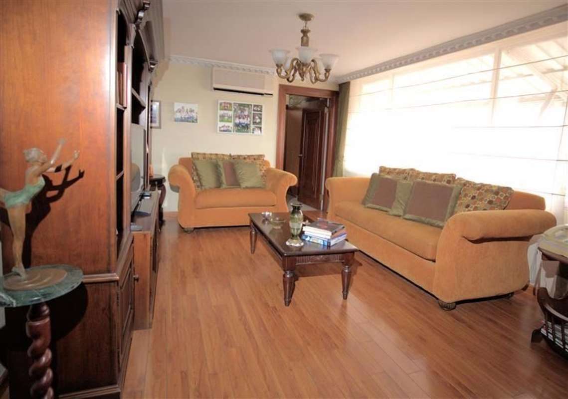 Traditional living room with large window, hardwood floors and entertainment center at PH Lalique Punta Paitilla