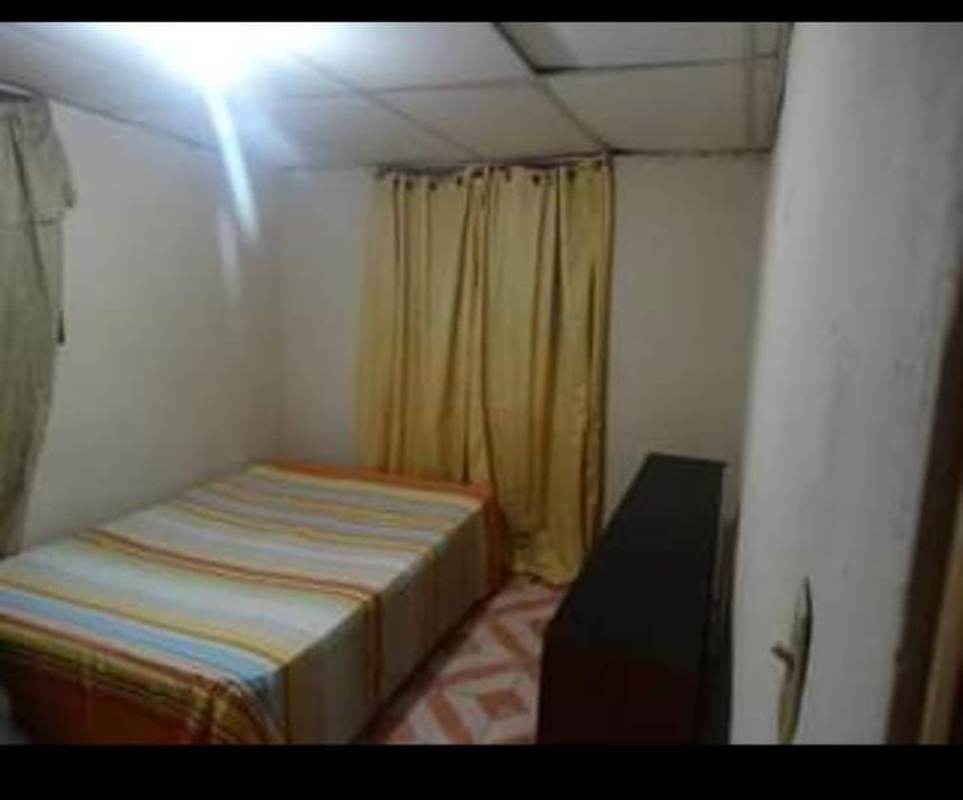Furnished bedroom in affordable studio with striped bedding, yellow curtains in Pedregal Panama City