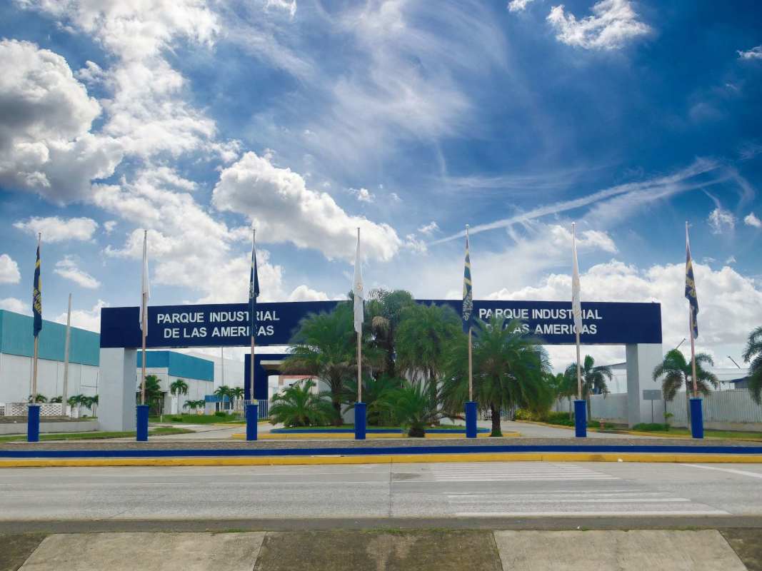 Gated secure entrance of Parque Industrial Las Americas Pacora with signage and palm landscaping