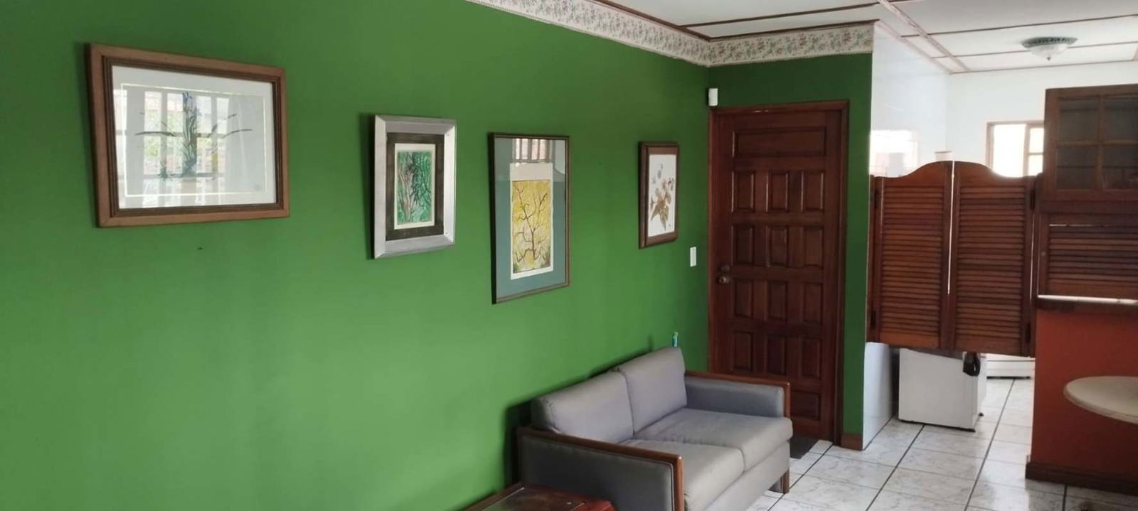 Living room with green wall, ceramic tile floor and wood furnishings in Coco del Mar house for rent