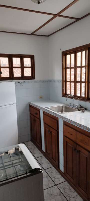 Kitchen with wood cabinetry, tile counters, gas stove and double window in Coco del Mar Panama