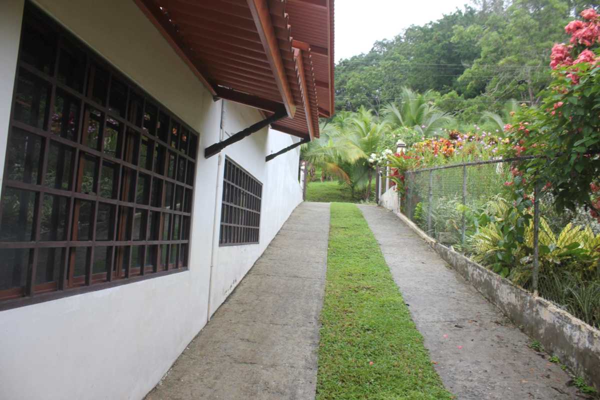 House side featuring barred windows, garden with trees, lush yard in Las Lajas Panama