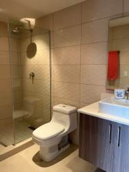 Bathroom with glass-enclosed shower, vanity and tile walls at PH Madeira
