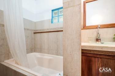 Rustic tiled bathroom with bathtub, vessel sink, blue-trimmed window in Jaramillo mountain home