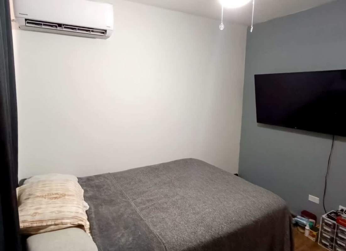Modern minimalist bedroom with split air conditioner, wall TV, and hardwood flooring in PH Nuevo Hato Pintado Panama