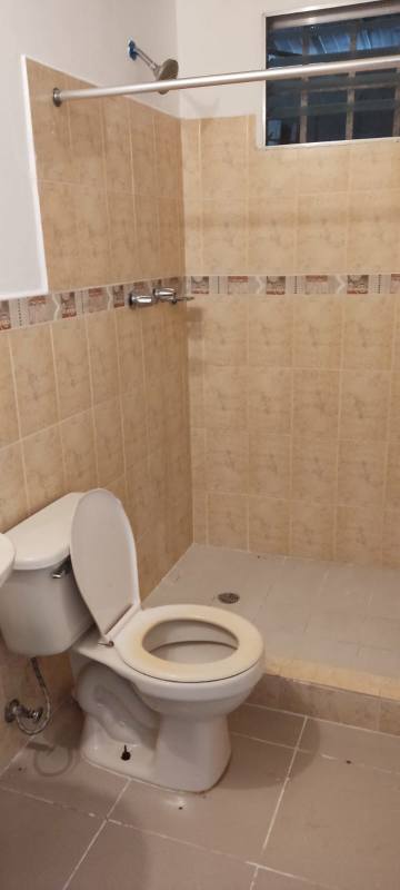 Simple bathroom with walk-in shower, toilet, beige tiles and window in double lot house Panama