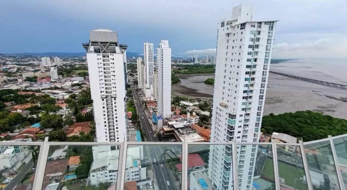 Living room or bedroom with large glass window facing ocean in luxury Panama City apartment PH Victory Wellness