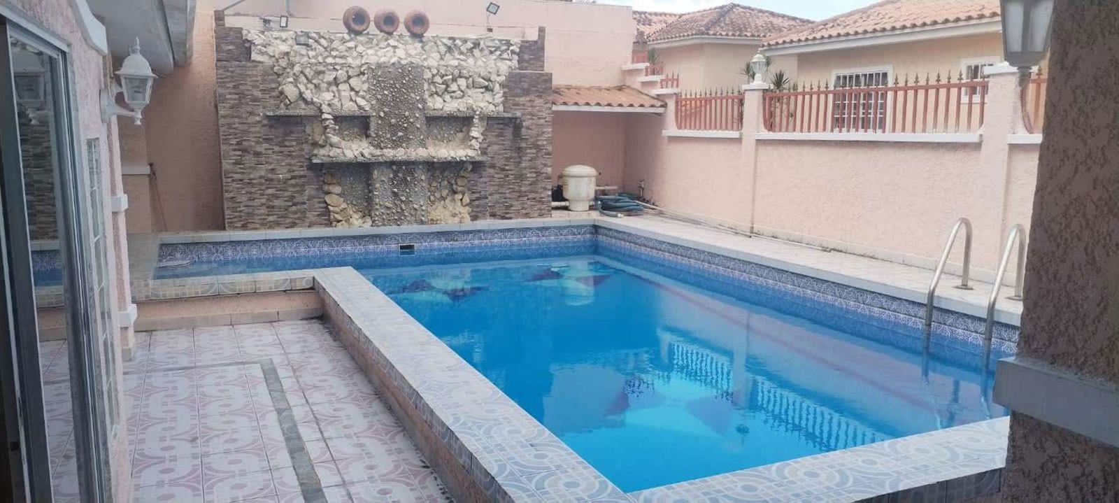 Private outdoor swimming pool with decorative waterfall feature tiled deck Fuente del Fresno Panama house for rent