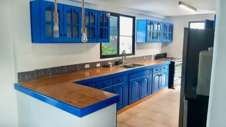 Covered terrace lounge with ceiling fan, seating and garden view beach house Costa Esmeralda Panama