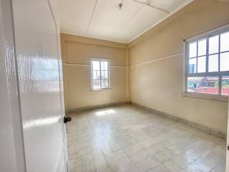 Simple bedroom with tiled floor, two windows and high ceiling in La Riviera apartment complex