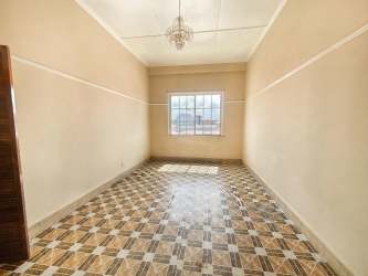 Empty room with tiled floor, chandelier and large window in investment building Colón