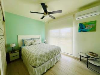 Bright bedroom with light decor, large window, ceiling fan in Playa Caracol beachfront condo