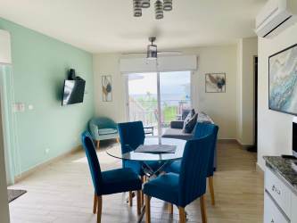 Living-dining area with floor-to-ceiling windows, coastal decor, balcony with sea view in Playa Caracol condo