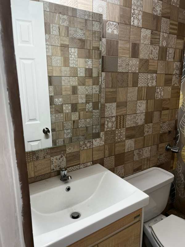 Bathroom featuring decorative patterned wall tile, white sink and toilet in PH Mystic Hills Villa Lucre