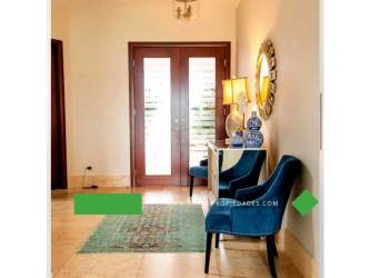 Spacious foyer with wooden double doors, blue chairs, console table, and marble flooring in Santa María estate Panama