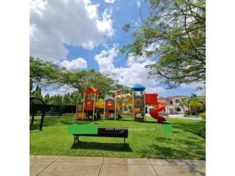 Colorful children’s playground with open lawn surrounded by trees in Santa María Golf & Country Club Panama