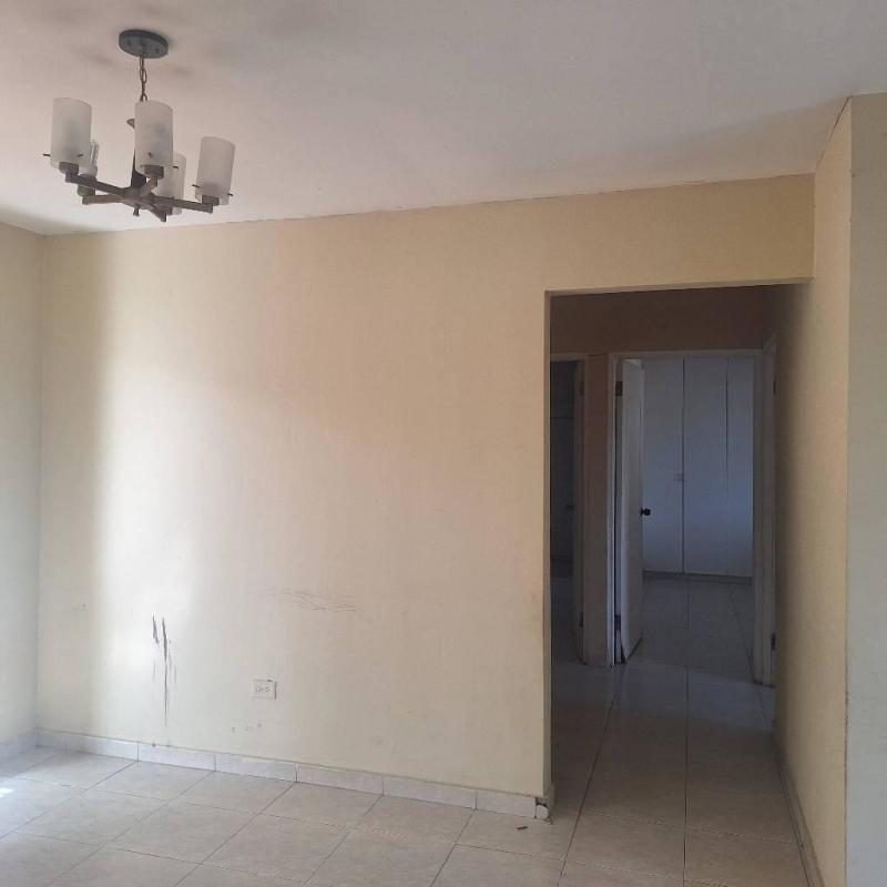 Empty interior room with tile floors, beige walls, and overhead chandelier inside Villa Zaita house Panama rental