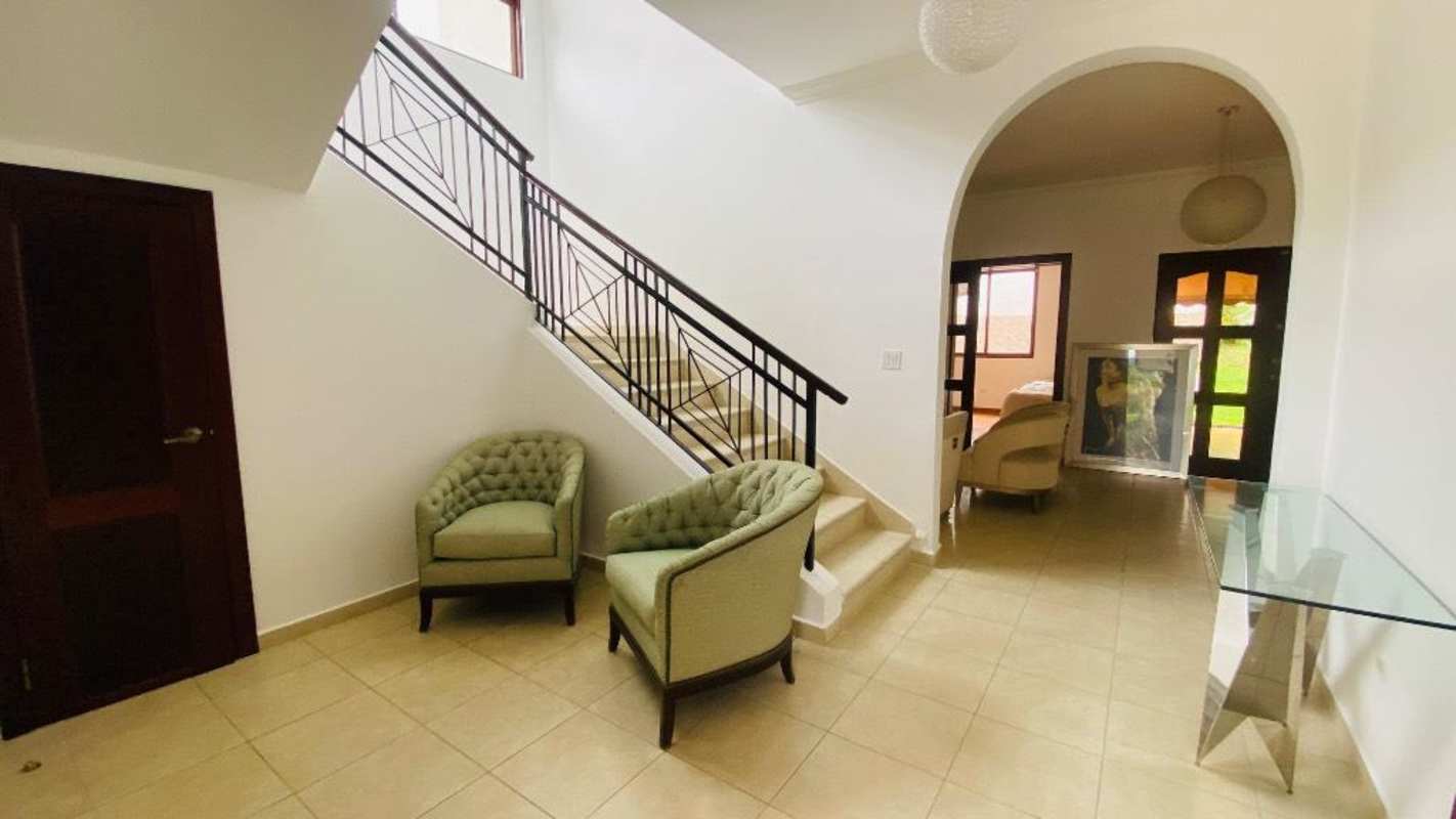 Entrance hall with black metal railing staircase, armchairs in Villa de las Fuentes Panama City