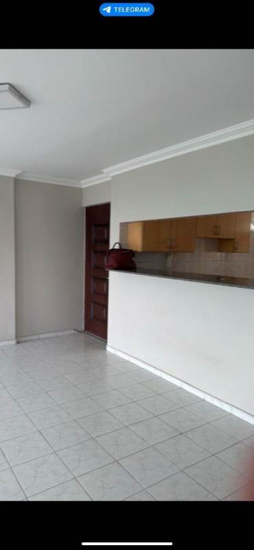 Living room with tiled floors and kitchen cutout in Villa de las Fuentes Panama