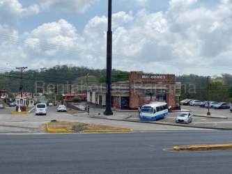 View of paved Transistmica road next to grassy lot with commercial signage in Sabanitas Colon