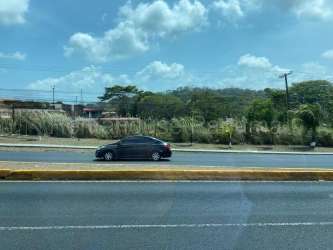 Grassy vacant lot with roadside signage ideal for retail plaza development in Colón Panama