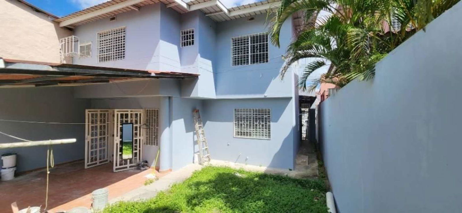 Backyard of two-story home with garden lawn, covered patio, security bars PH Colinas del Golf Brisas del Golf Panama