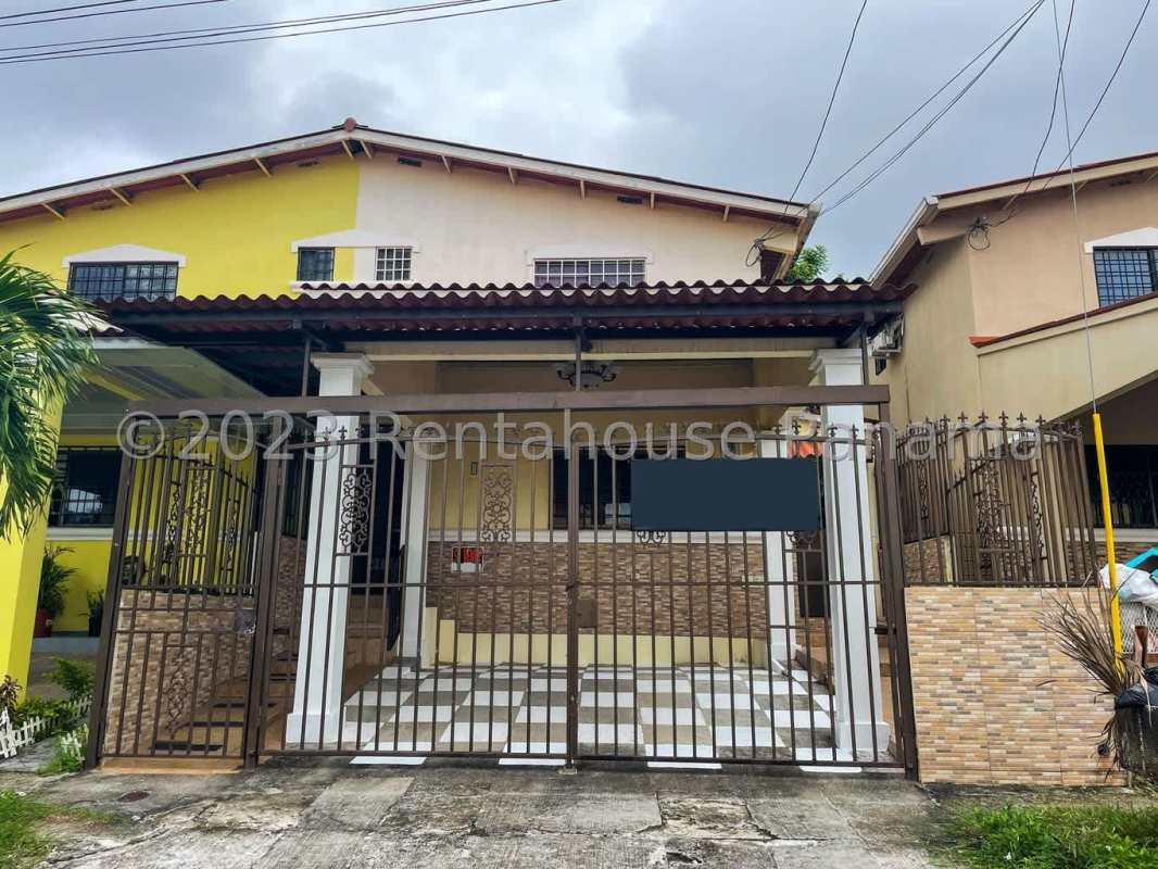 Yellow house with white accents, metal gate, covered porch, driveway in Cerro Viento Panama