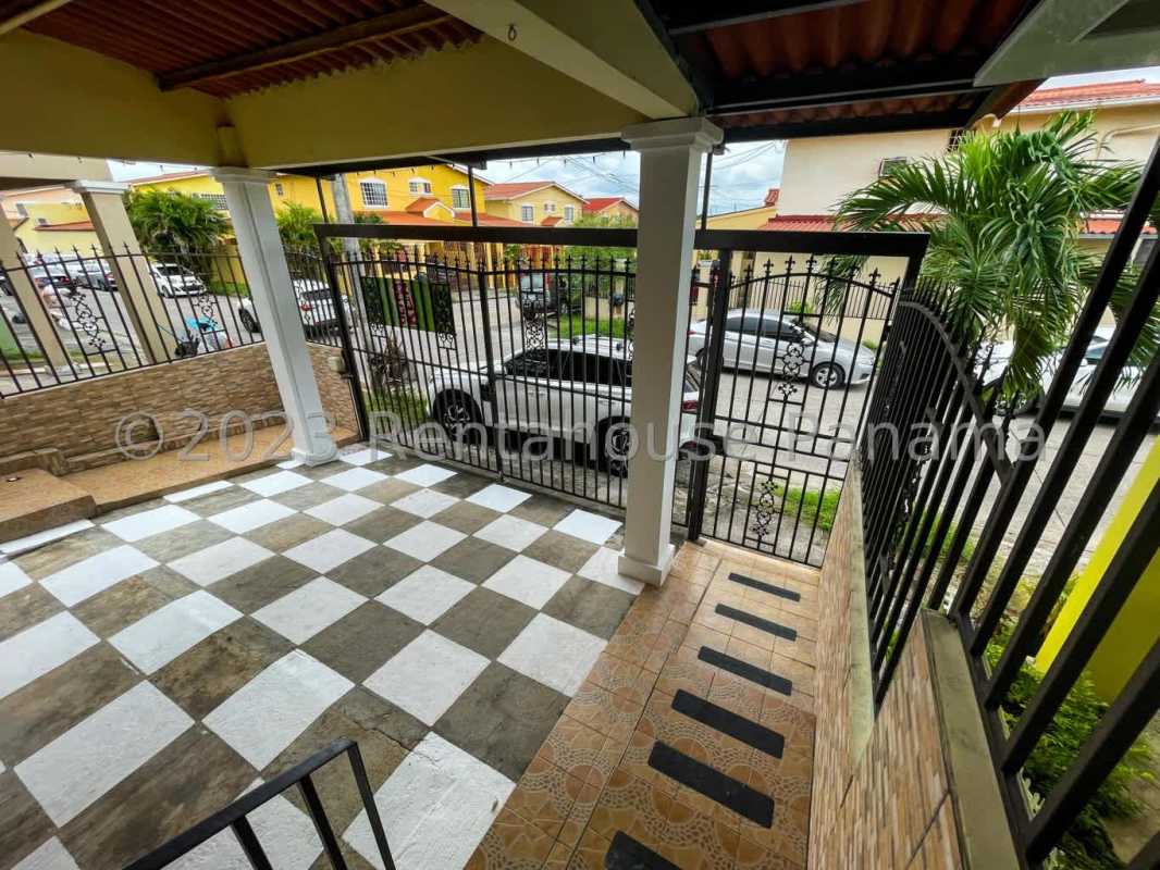 Gated covered porch with checkered tile flooring, metal gate in house Cerro Viento Panama