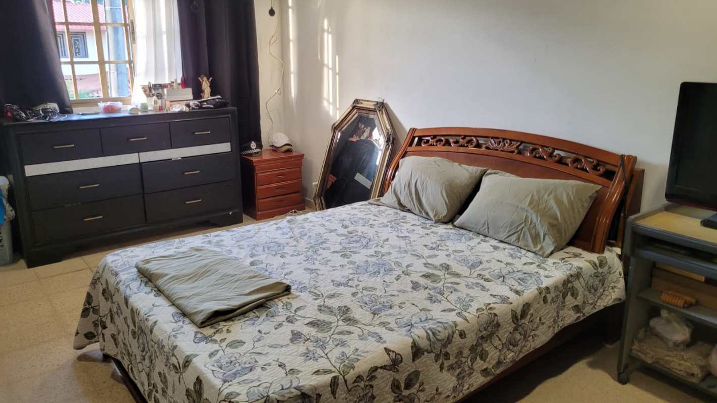 Spacious traditional bedroom with wooden bed and dresser, window view in duplex rental