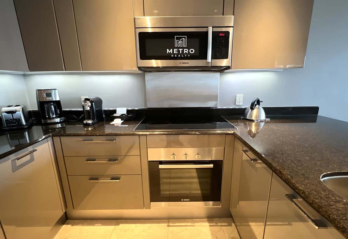 Open kitchen in luxury condo-hotel suite with granite counters and stainless appliances