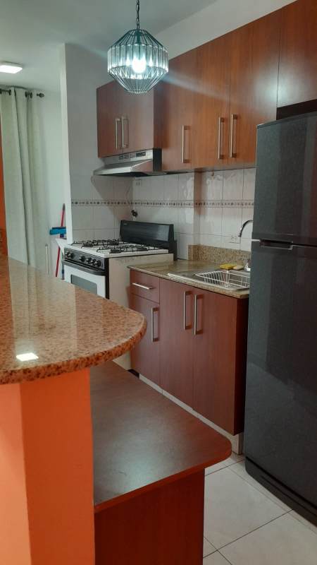Kitchen with granite countertop, wooden cabinets, gas stove, refrigerator in Villa Margarita Parque Lefevre