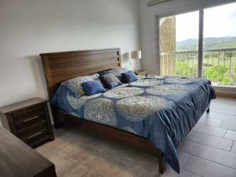 Modern bedroom with balcony views over forest and skyline at Forest Tower Panama Pacifico
