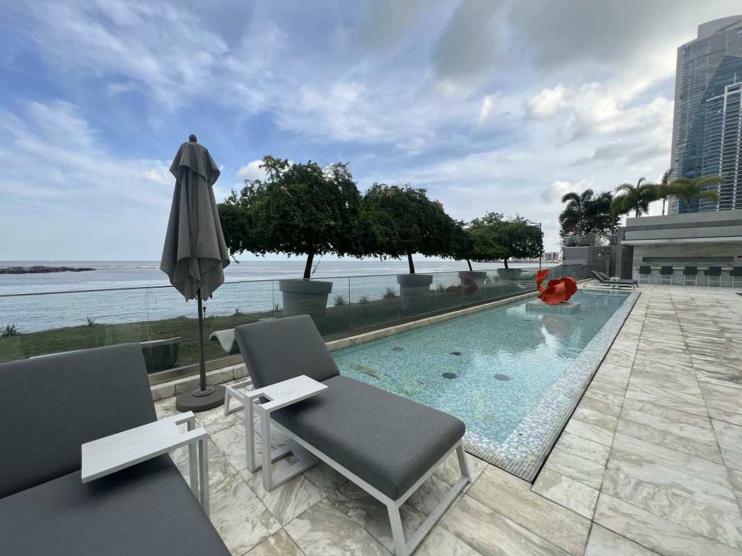 Spacious living room with marble floors, wraparound floor-to-ceiling windows with ocean and skyline views in PH Ocean Residences Panama